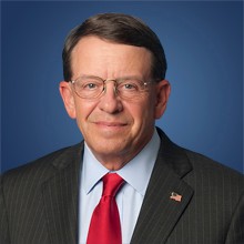 Headshot of Edward Ludwig in black coat and smiling face.