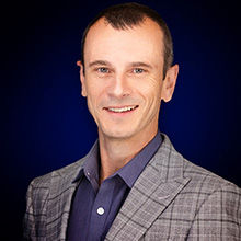 Headshot of Paudie Connor in check coat and smiling face.