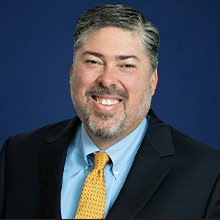 Headshot of Brad Sorenson in black coat and smiling face.