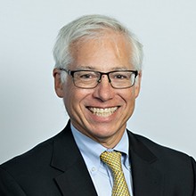 Headshot of Dr Ken Stein in black coat and smiling face.